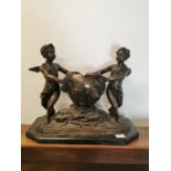 Bronze urn and cherubs on a marble plinth.