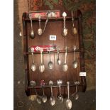 PINE STAINED RACK OF SOUVENIR AND ENAMEL FINIAL TEASPOONS