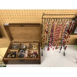 WOODEN BOX OF VARIOUS COSTUME JEWELLERY AND A RACK OF BEAD NECKLACES