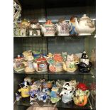 THREE SHELVES OF NOVELTY TEAPOTS INCLUDING SADDLERS EXAMPLES
