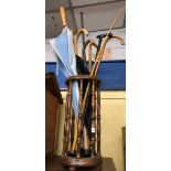 BEECH TURNED SPINDLE CYLINDRICAL CANE STAND AND A SELECTION OF UMBRELLAS,