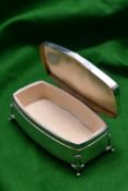 A silver trinket box on raised feet with blue guilloché enamel panel in lid and padded interior.