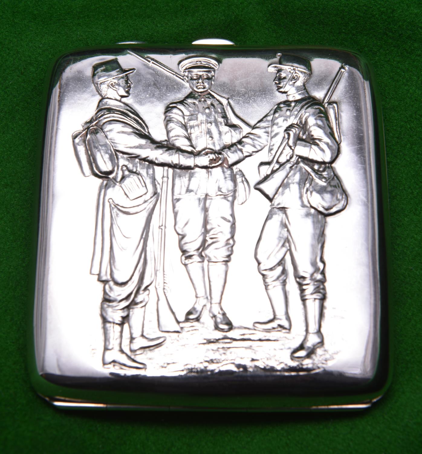 A silver cigarette case with relief decoration of three early 20thC soldiers to lid and gilt wash