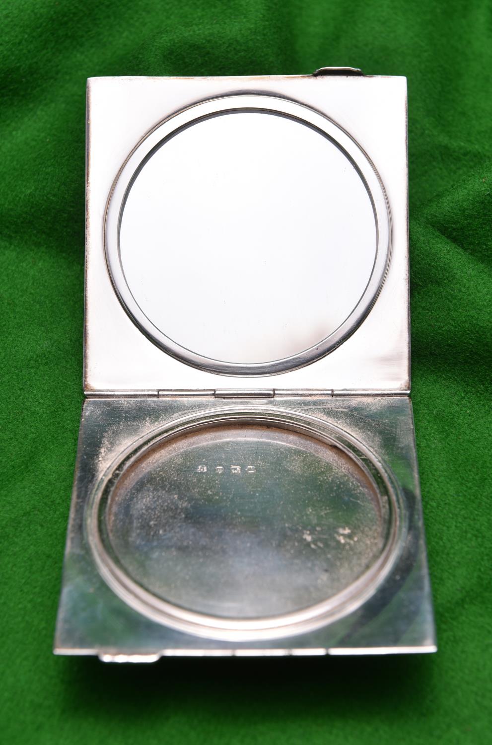 A silver powder compact with engine turned case, blue guilloché enamel lid and fitted mirror inside.