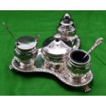 A decorative silver 4-piece condiment set. On a triangular stand raised on 3 feet with blue glass