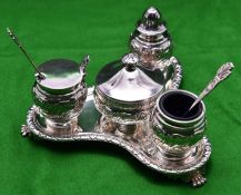 A decorative silver 4-piece condiment set. On a triangular stand raised on 3 feet with blue glass