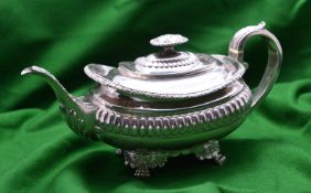 A Georgian rounded rectangular silver teapot with gadrooning decoration to the body, leaf-embossed