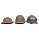A WWII British steel helmet; a US style steel helmet; another similar (lining missing, bullet hole