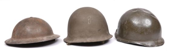 A WWII British steel helmet; a US style steel helmet; another similar (lining missing, bullet hole