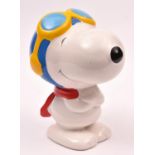 A large ceramic Snoopy character money box standing with red scarf in blue flying helmet and with