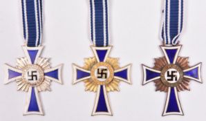 Third Reich Mother’s Cross, in gold, silver and bronze, with ribbons. VGC; together with printed