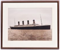 A framed sepia black and white photograph of Titanic. Mounted within a wood cream carded frame