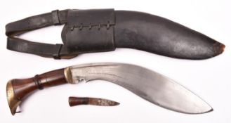 A kukri, probably mid 20th century, blade 11", with brass mounted polished wood hilt, in its leather