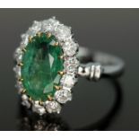 An emerald and diamond ring, the central oval cut and claw emerald approx. 2.40ct, surrounded by