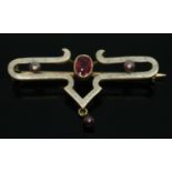 An enamel brooch set with a central oval cut ruby and three cultured pearls, marked 18, length 42mm,