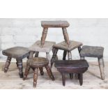 A group of seven wooden milking stools, heights ranging from 18cm to 26cm.