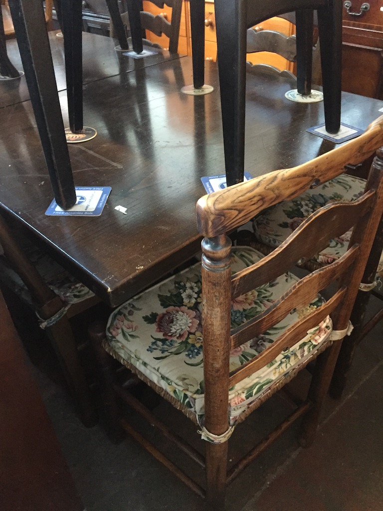 An oak extending dining table and four rush seated ladder back chairs together with an additional