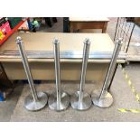 A chrome finish queue barrier with four stanchions.