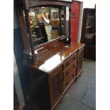 A large oak mirror back sideboard with carved panel cupboard doors and arts and crafts drawer