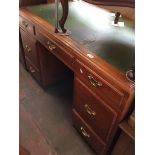 An oak pedestal desk with green leather writing surface and brass handles.