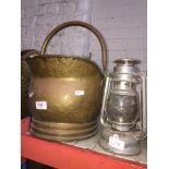 A brass coal bucket and Tilley lamp