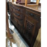 An antique mahogany sideboard with carved door panels and drawer fronts and aesthetic handles.