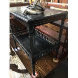 An ebonised two tier trolley table with turned spindles and legs.