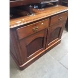 A mahogany sideboard with two drawers above cupboard