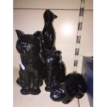 Four black pottery cats