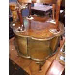 A 1930s figured walnut revolving bookcase coffee table with cabriole legs, diam. 65cm.