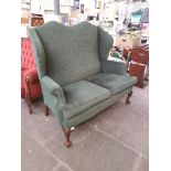 A Queen Anne style green upholstered wing back settee.