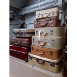 A stack of eight vintage cases and a modern red Antler suitcase.