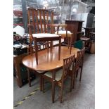 A teak oval extending dining table and six chairs.