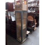 A glazed corner display cabinet and a small rustic table with drawer.
