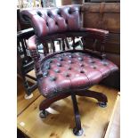 A reproduction red buttoned and studded leather captain's swivel chair.