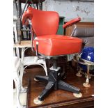 An American style chrome barber's chair with red vinyl upholstery.