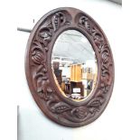 A carved framed oval mirror 53cm x 66cm.