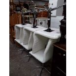 A set of six white/cream leather effect swivel dining chairs.