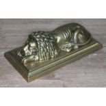 A cast brass paperweight modelled as a recumbent lion on plinth, length 19cm.