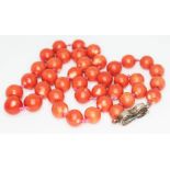 A single strand of coral beads with enamel and filigree clasp marked Silver, beads diam. approx. 9mm
