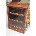 A three part mahogany sectional bookcase of shaped form with gallery, faux columns and lower drawer,