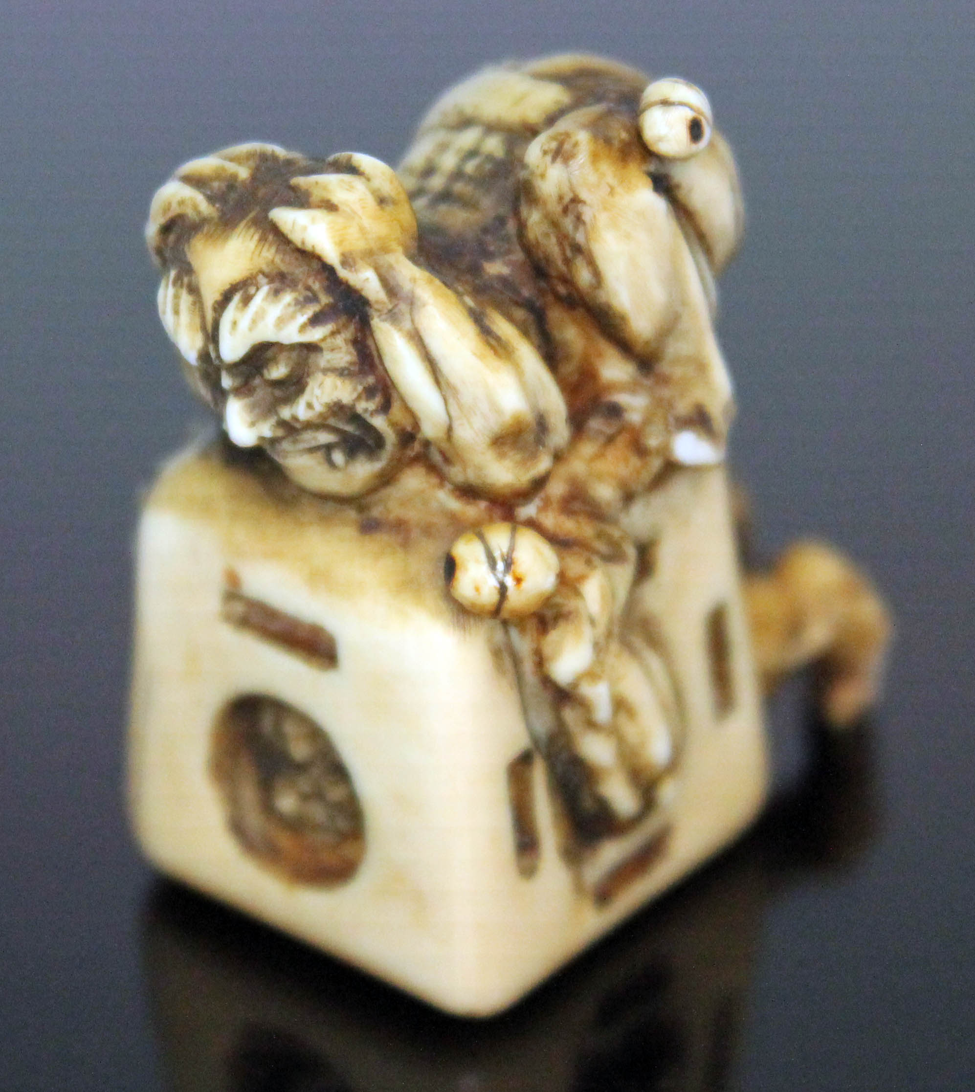 A Japanese carved ivory netsuke formed as an oni catcher on top of a box with protruding limbs,