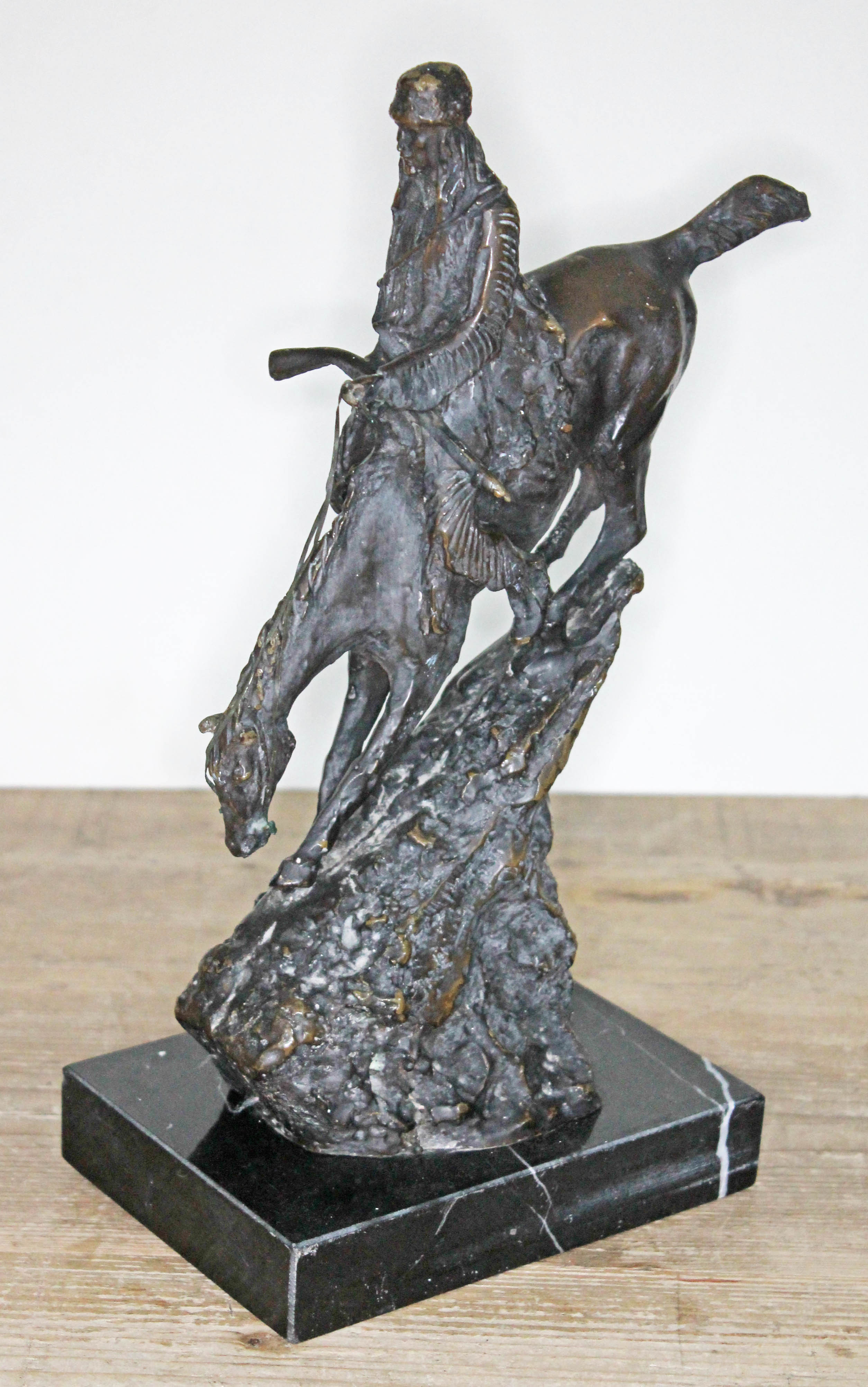 A modern bronze depicting a Native American riding a bucking horse on marble base, height 34cm.