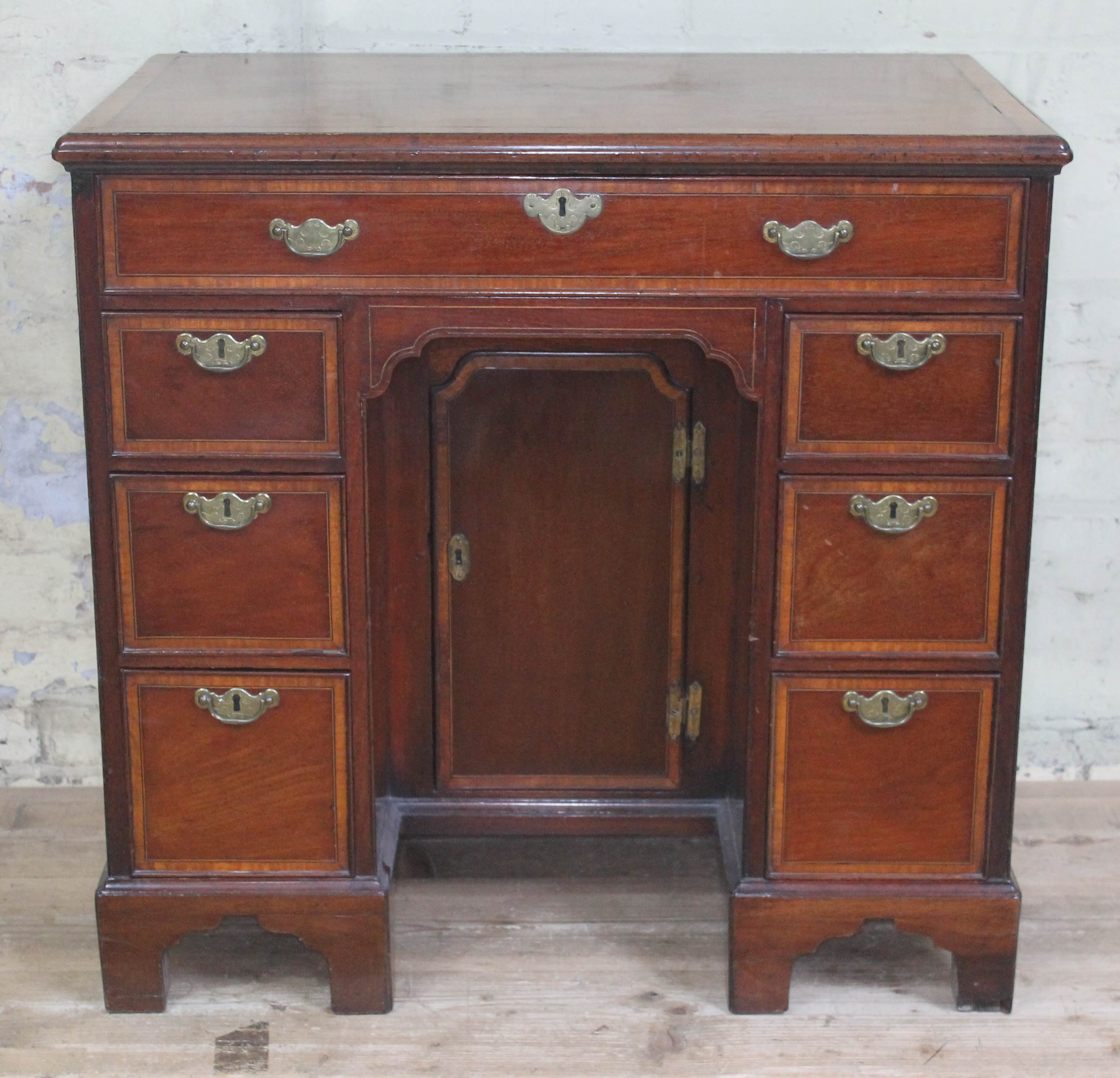 A George III mahogany knee hole desk, cross-banded top with moulded edge above one long and six