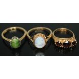 A group of three rings comprising a green cabochon ring marked 18ct, a ring set with an opal triplet