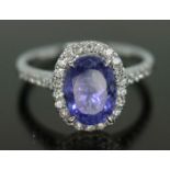 A tanzanite and diamond cluster ring, the central bluish purple oval cut stone weighing approx. 3ct,