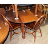 An oak extending dining table with one leaf and four spindle back and elm seated chairs with