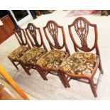 A set of four George III mahogany chairs in the manner of Hepplewhite with shield backs carved