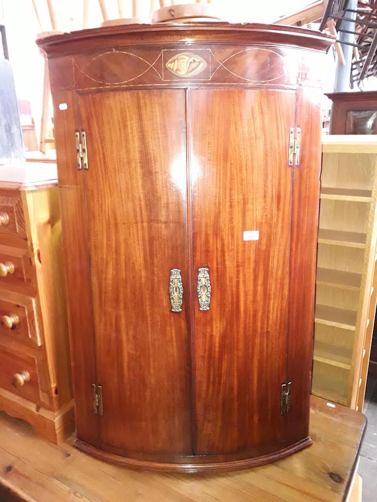 A Georgian mahogany bow front corner cabinet with shell inlay.