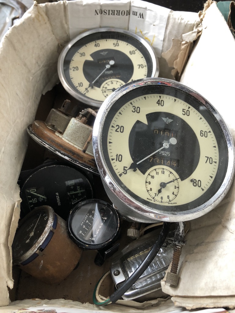 A box containing vintage car speedometers and other dials